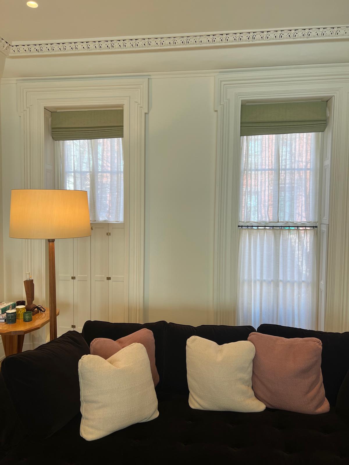 Sage green roman shades with black sofa in elegant room
