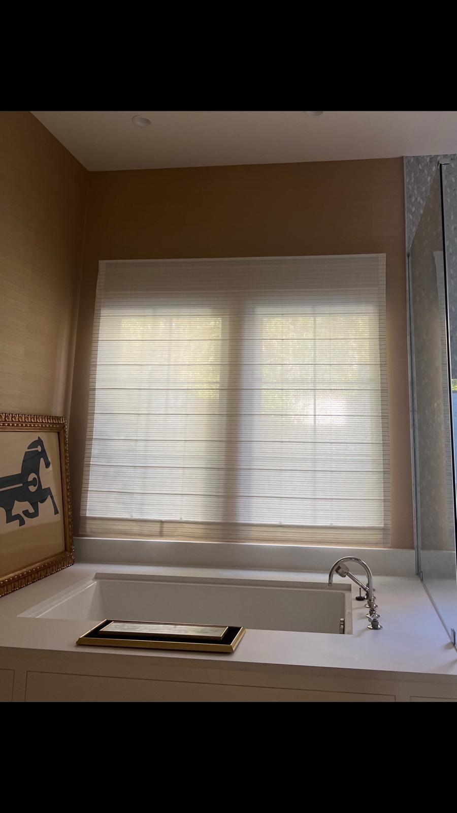 Roman shade installed above soaking tub in bathroom