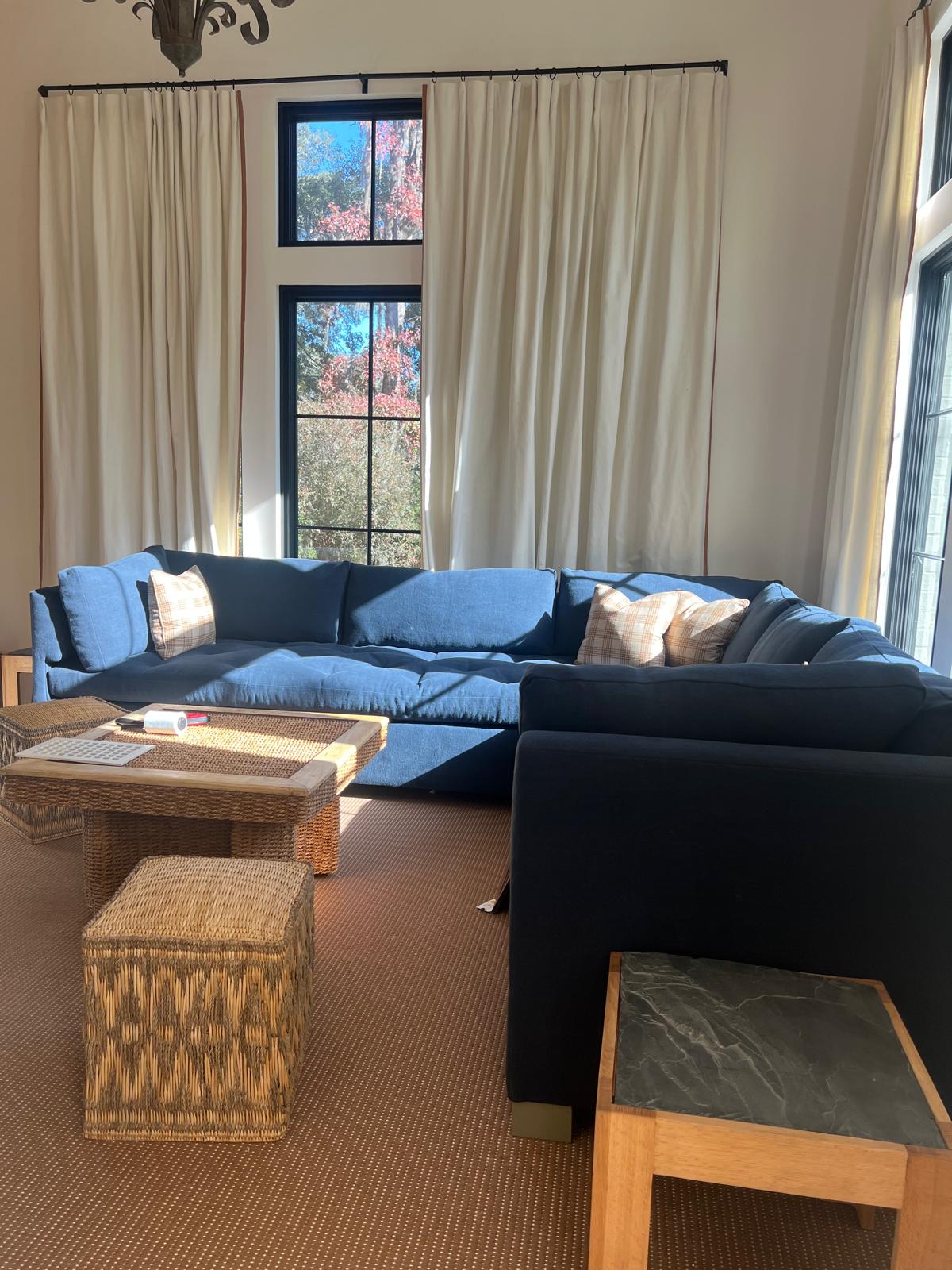 Large blue sectional sofa with floor-length drapes