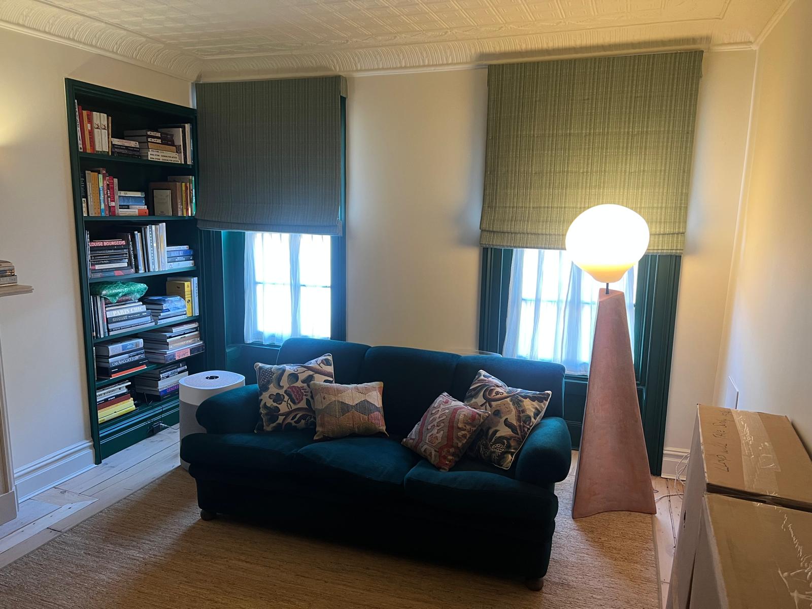 Teal velvet sofa with green roman shades