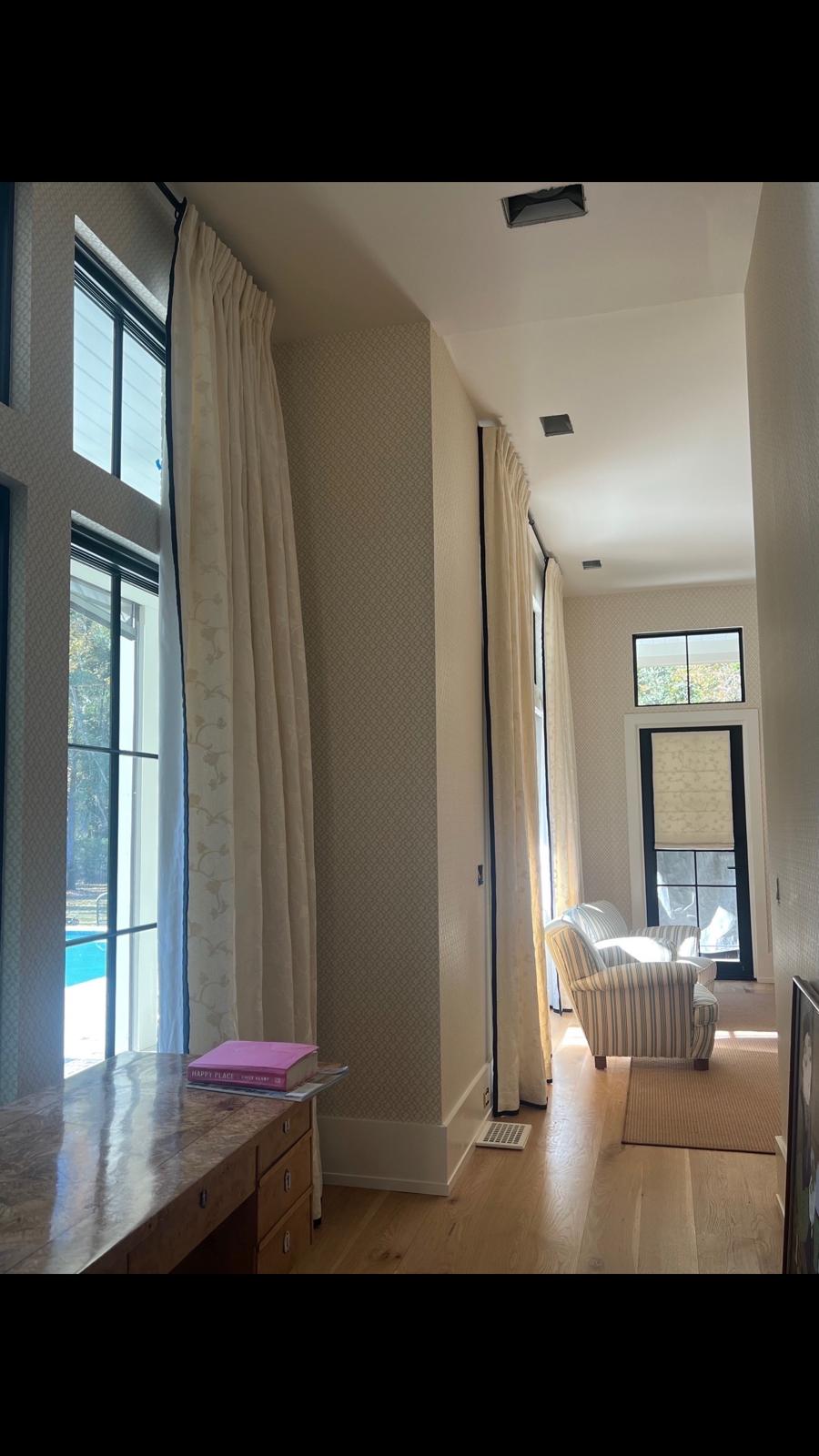 Floor-to-ceiling drapes in hallway with striped chair