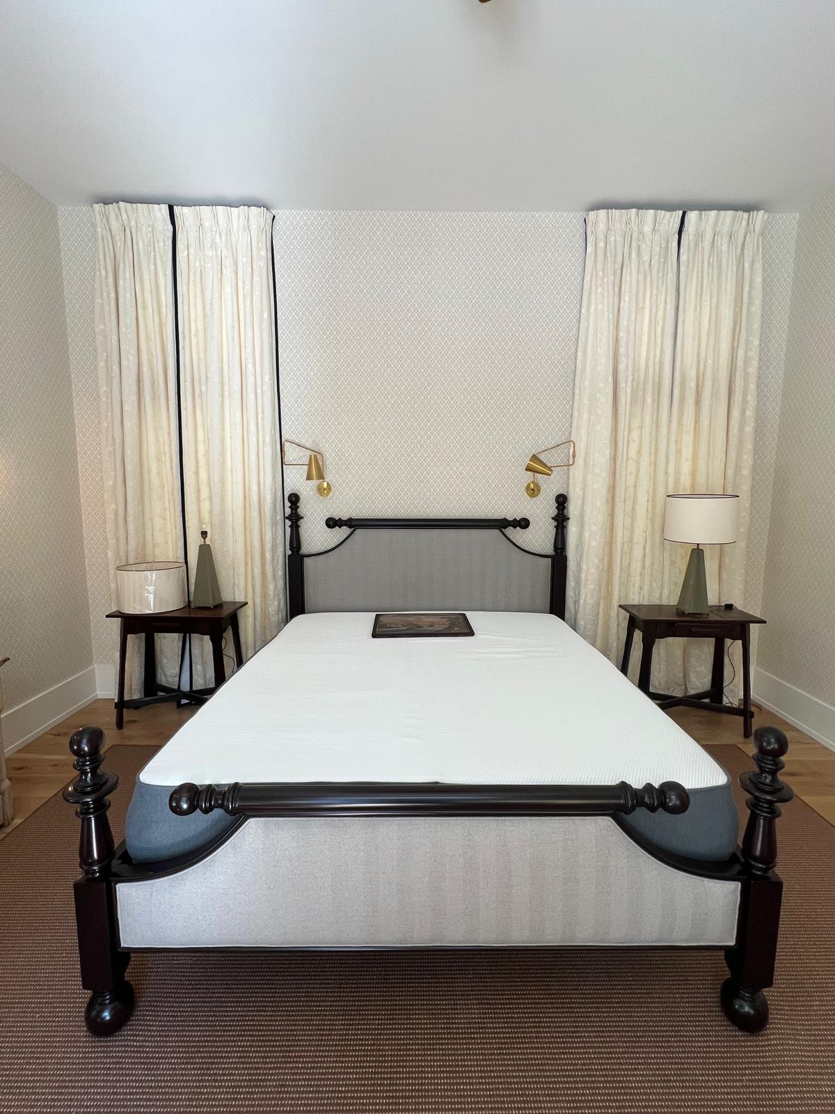 Gray upholstered bed frame with floor-length drapes