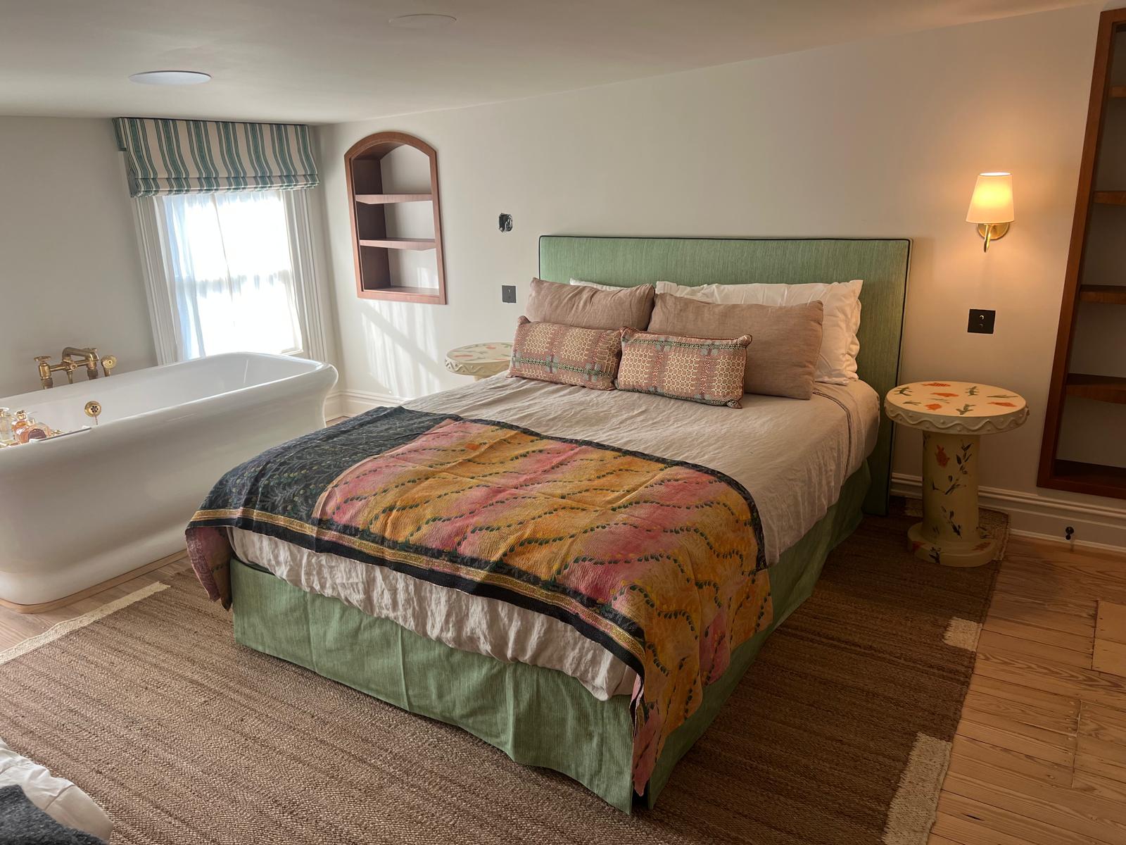 Green upholstered bed frame in striped bedroom