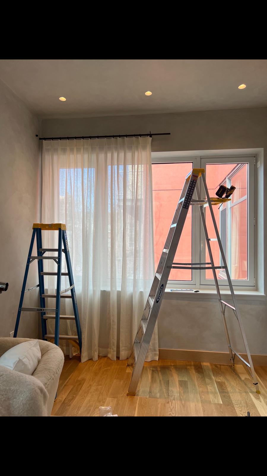 Sheer drapes being installed on ceiling-height rod