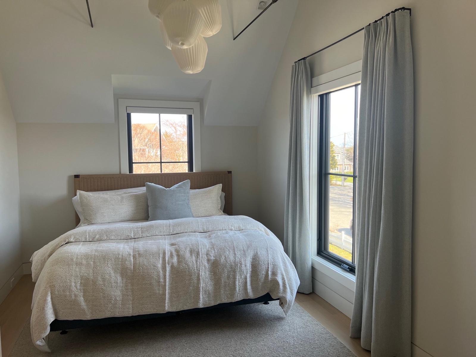 Gray drapes in bedroom with woven headboard