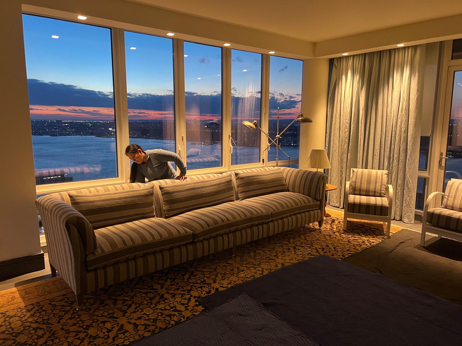 Large striped sofa being installed in luxury high-rise apartment at sunset